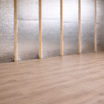 Binnenmuur met houten stijlen en PIR isolatieplaten met aluminium cachering, geplaatst tegen de wand boven een afgewerkte laminaatvloer.