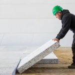 Meneer van de bouw legt EPS plaat op de zandvloer