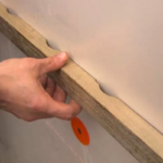 Close-up van meneer die ventilatielat bevestigt.